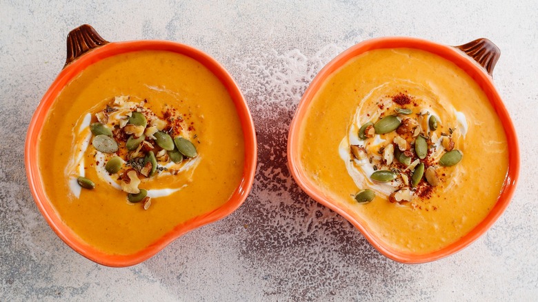 Bowls of creamy pumpkin soup with pepitas on top