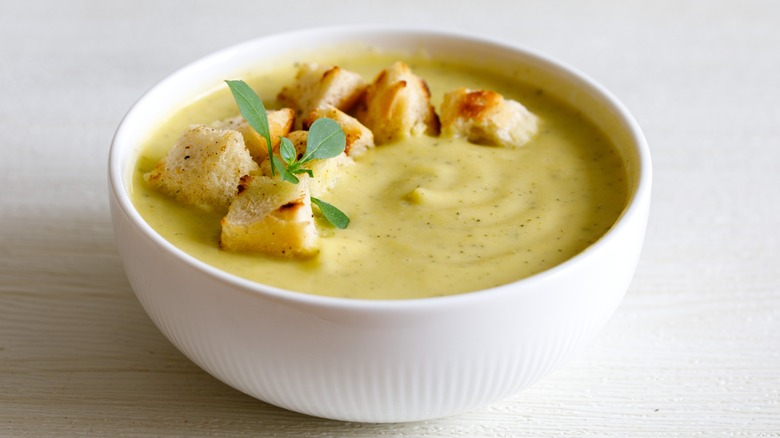 White bowl with creamy zucchini soup and croutons