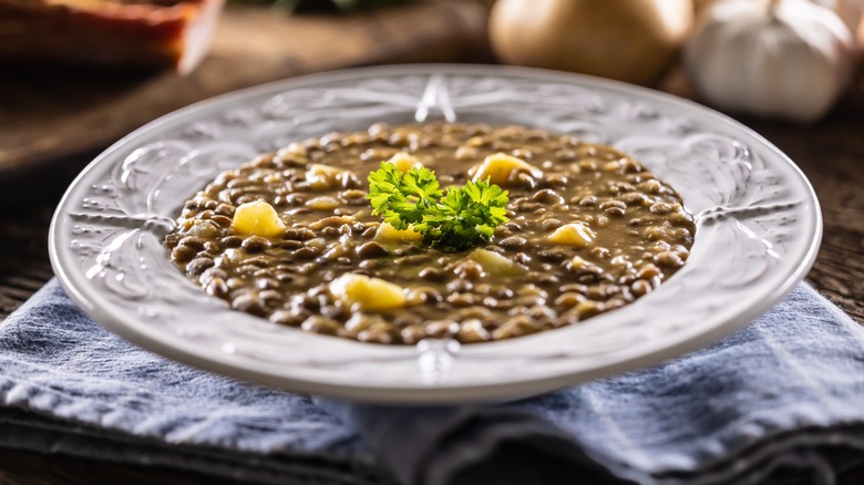 Bowl of lentil and potato soup with green herb garnish