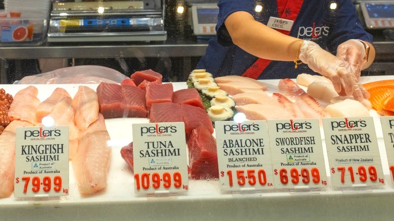 Different types of sushi grade fish on a market counter.