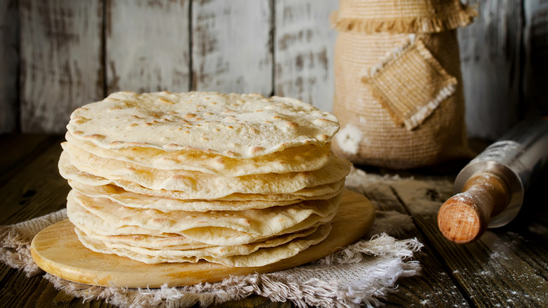 stack of flour tortillas next to rolling pin