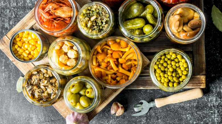 Jars of assorted pickled and marinated items on wooden boards