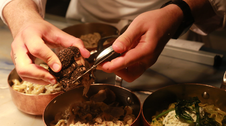 chef shaving truffles over pasta dish