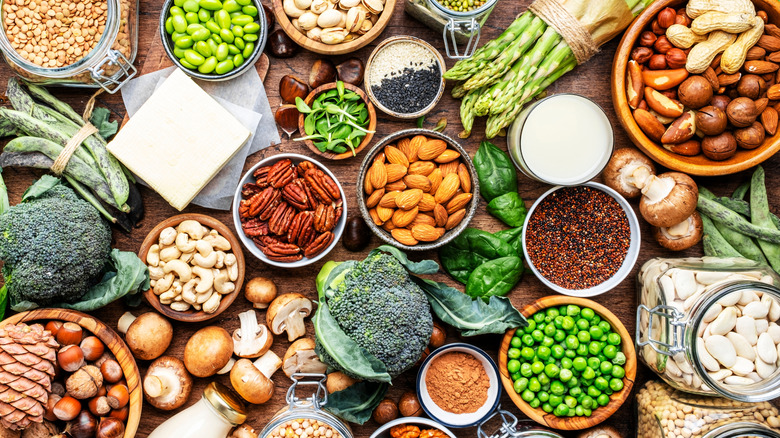 A colorful array of vegan protein sources and fresh vegetables sit on a wooden surface