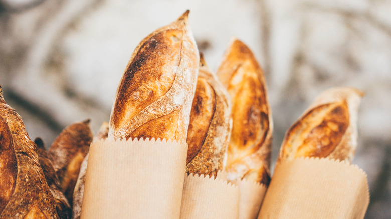 Tips of baked baguettes in brown paper bags.