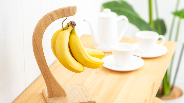 bananas hanging from a wooden fruit hanger