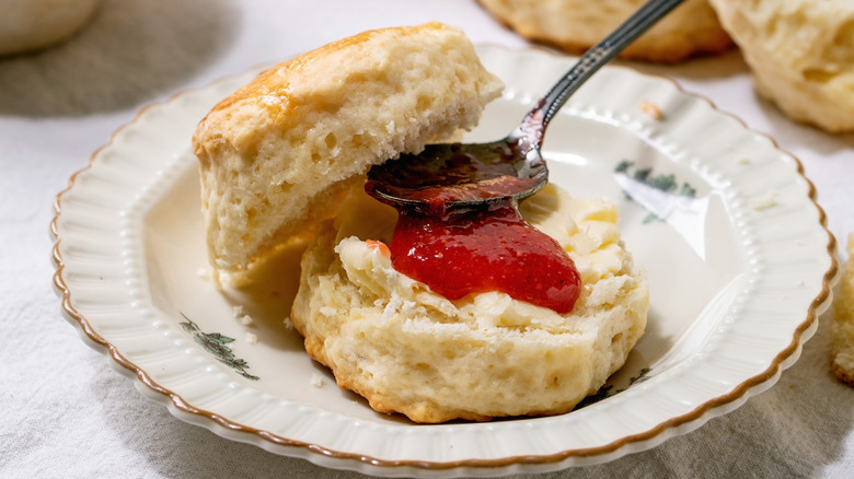 A biscuit cut in half and spread with jam sits on a decorative plate