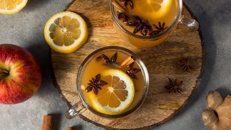 mulled apple cider on wood with lemon slices, apple, and ginger