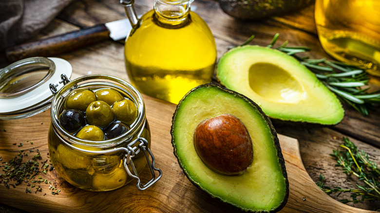 Halved avocado next to jar of olives