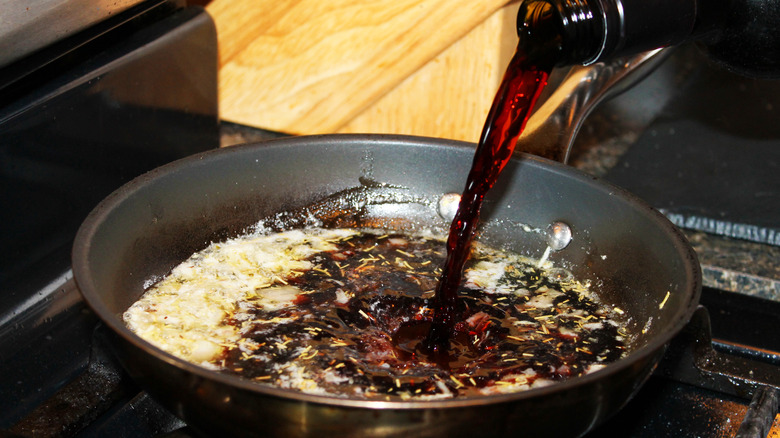 red wine being poured into pan sauce