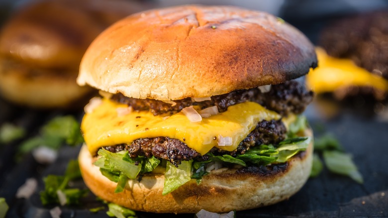 Double smash burger with cheese, diced onions, and lettuce on a toasted bun.