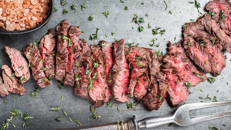 Cooked skirt steak sitting on a metal surface.