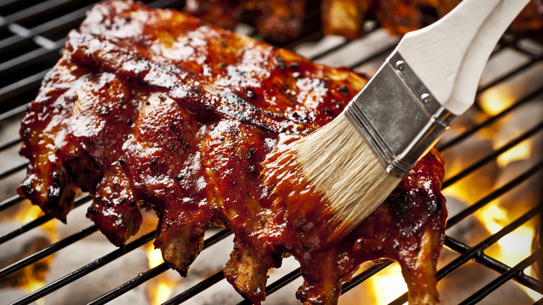 basting ribs with barbecue sauce on grill