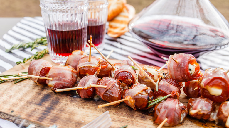 Bacon wrapped stuffed dates on table with wine