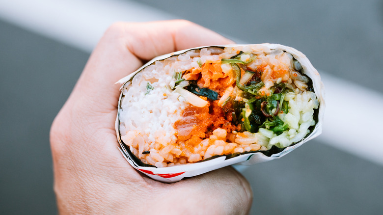 Person holding sushi burrito