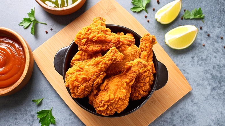 Fried chicken drumsticks in a bowl with dips