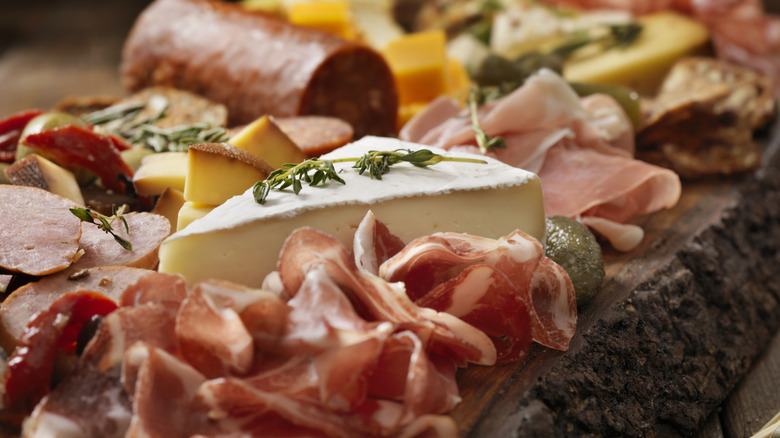 A closeup shows ingredients on a charcuterie board.