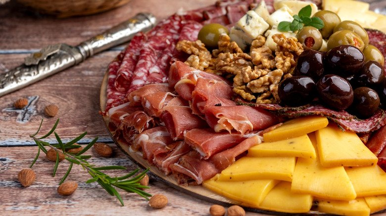 A charcuterie board with cheese, olives, nuts, and sliced cured meats