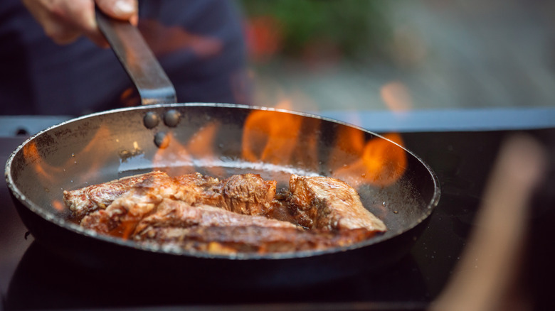 flambeing beef in flaming pan