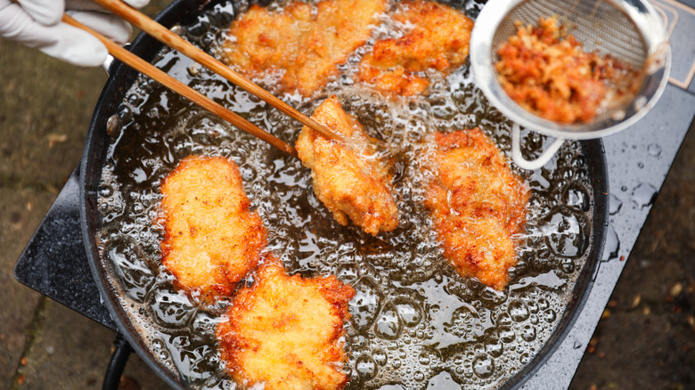 Crispy fried chicken pieces in bubbling oil