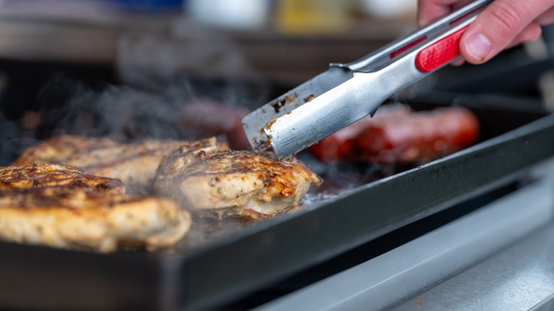 Cooking seasoned chicken breasts on a Blackstone