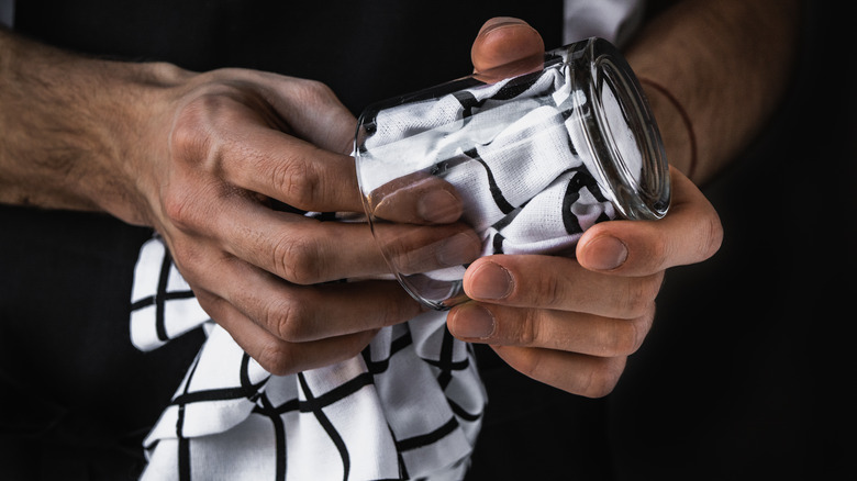 person cleaning cocktail glass with cloth