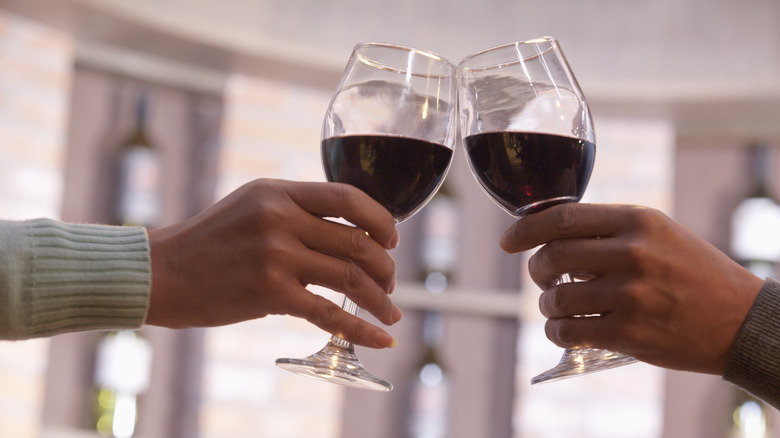 Two people toasting with red wine