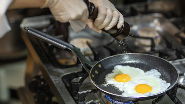 chef seasoning fried eggs with salt