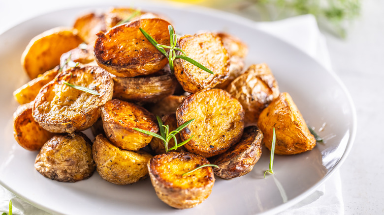 A plate of golden roasted potatoes on a white plate