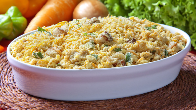 White dish of farofa with fresh vegetables in the background