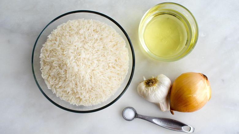 White rice in a bowl with an onion, garlic, oil, and salt at one side