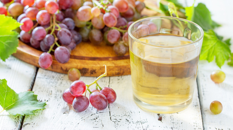 white grape juice by plate of grapes