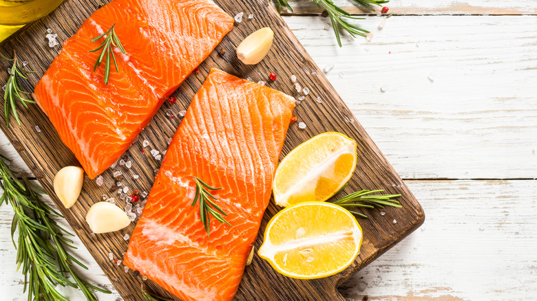 raw salmon filets on a wooden board with garlic and lemon