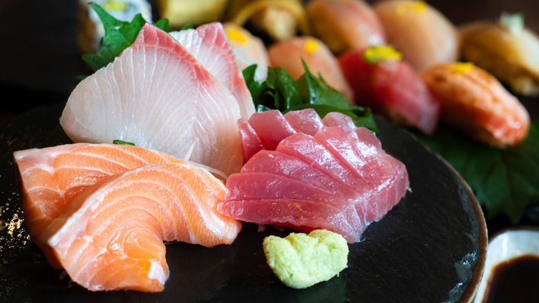 Se;ection of sashimi on plate including yellowtail, salmon, and tuna