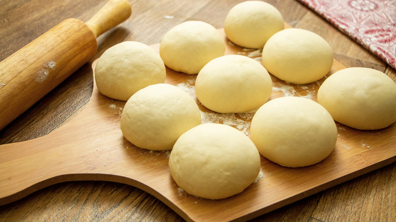 Balls of fresh pizza dough on a wooden paddle