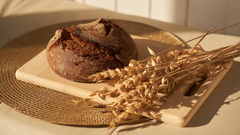 A rye sourdough loaf on a wooden cutting board.