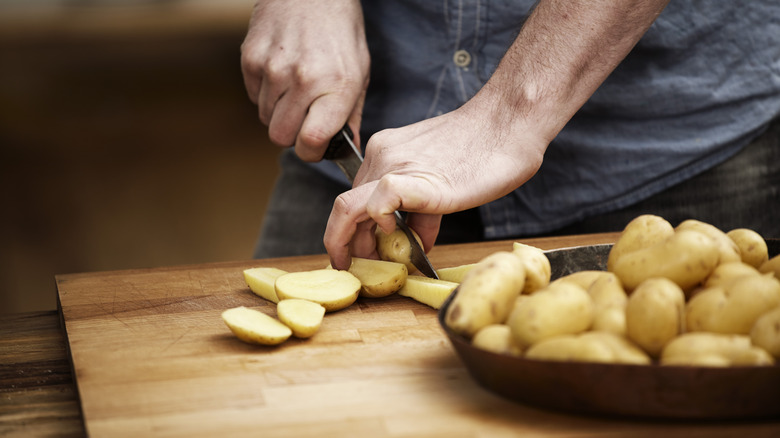 Chef slicing Yukon gold potatoes for cooking