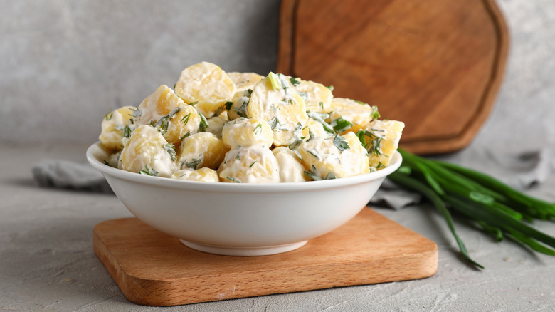 A bowl of creamy potato salad with green onions