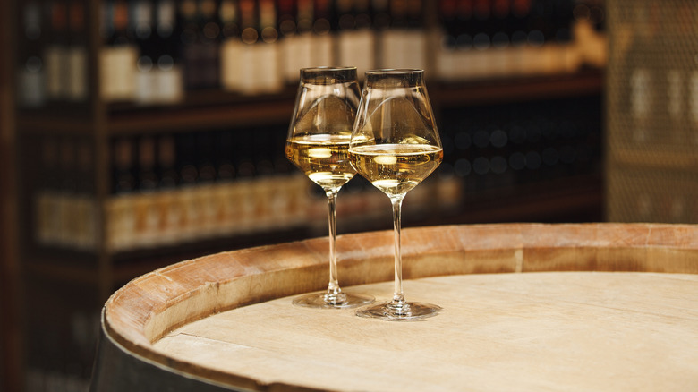 Two glasses of white wine on a wooden barrel