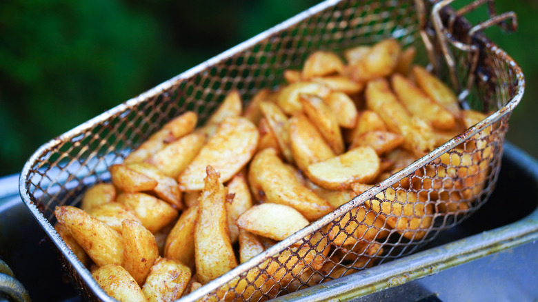 Basket of potato wedges lifted from deep fryer