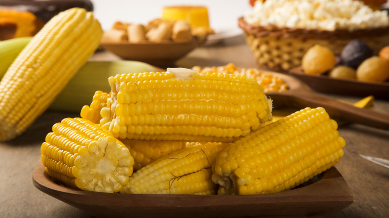 ears of cooked corn on the cob on a wooden plate