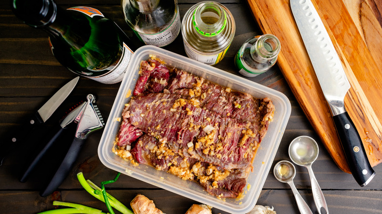 A skirt steak, another tough cut, marinating in a mix of soy, vinegar, and other condiments with fresh garlic and chives