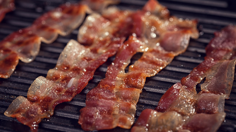 Strips of bacon cooking on grill grates