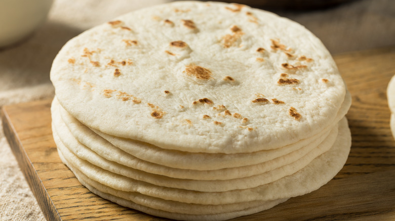 Stack of tortillas on a wooden cutting board