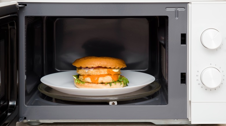 Burger on a white plate inside a microwave