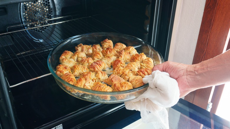 Person removing a glass tray from an oven