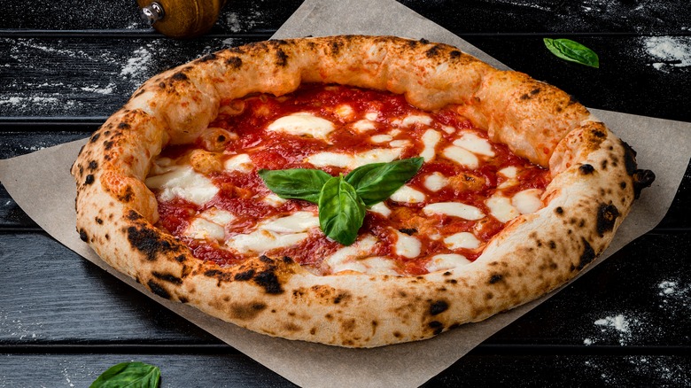 Unsliced margherita pizza with fresh basil