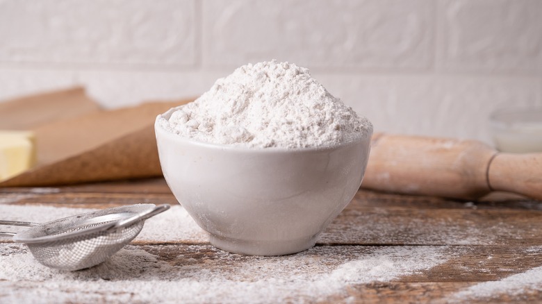 bowl of flour with sieve and rolling pin