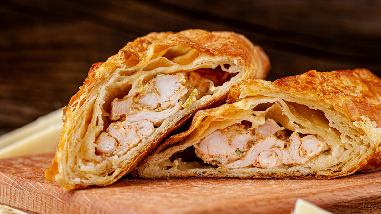 A pile of chicken hand pies sit on a wooden board