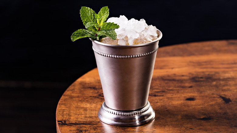 Mint julep cocktail in a silver cup on a table